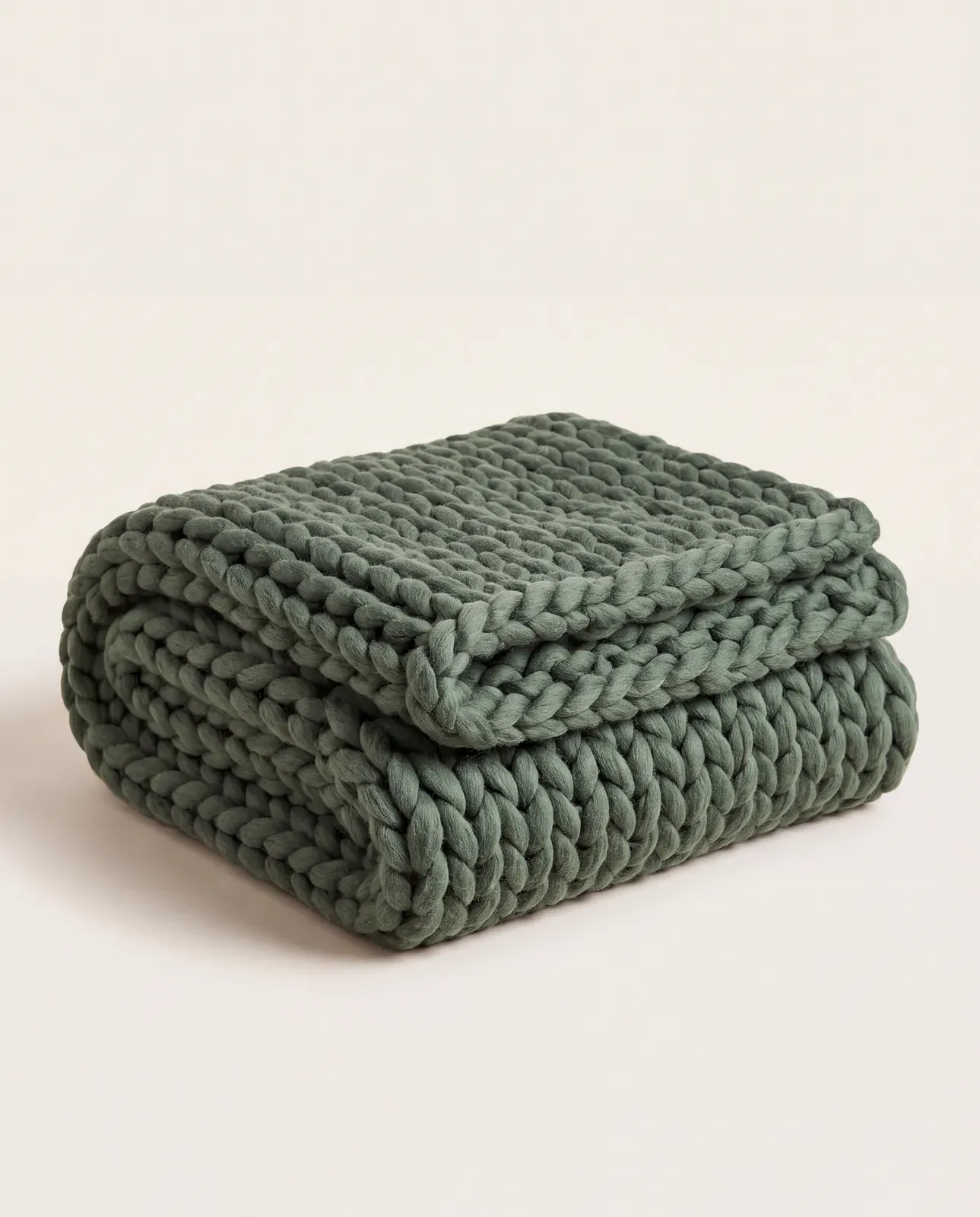 Green chunky-knit throw folded on a white background